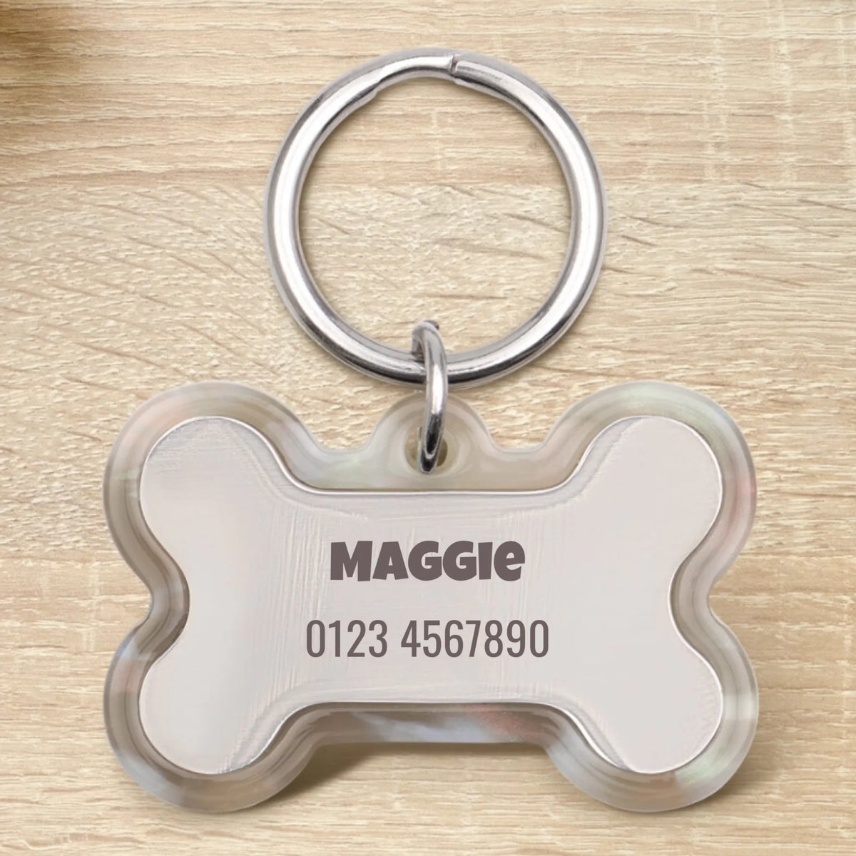Personalized bone-shaped epoxy dog tag with the name "Maggie" and a phone number.