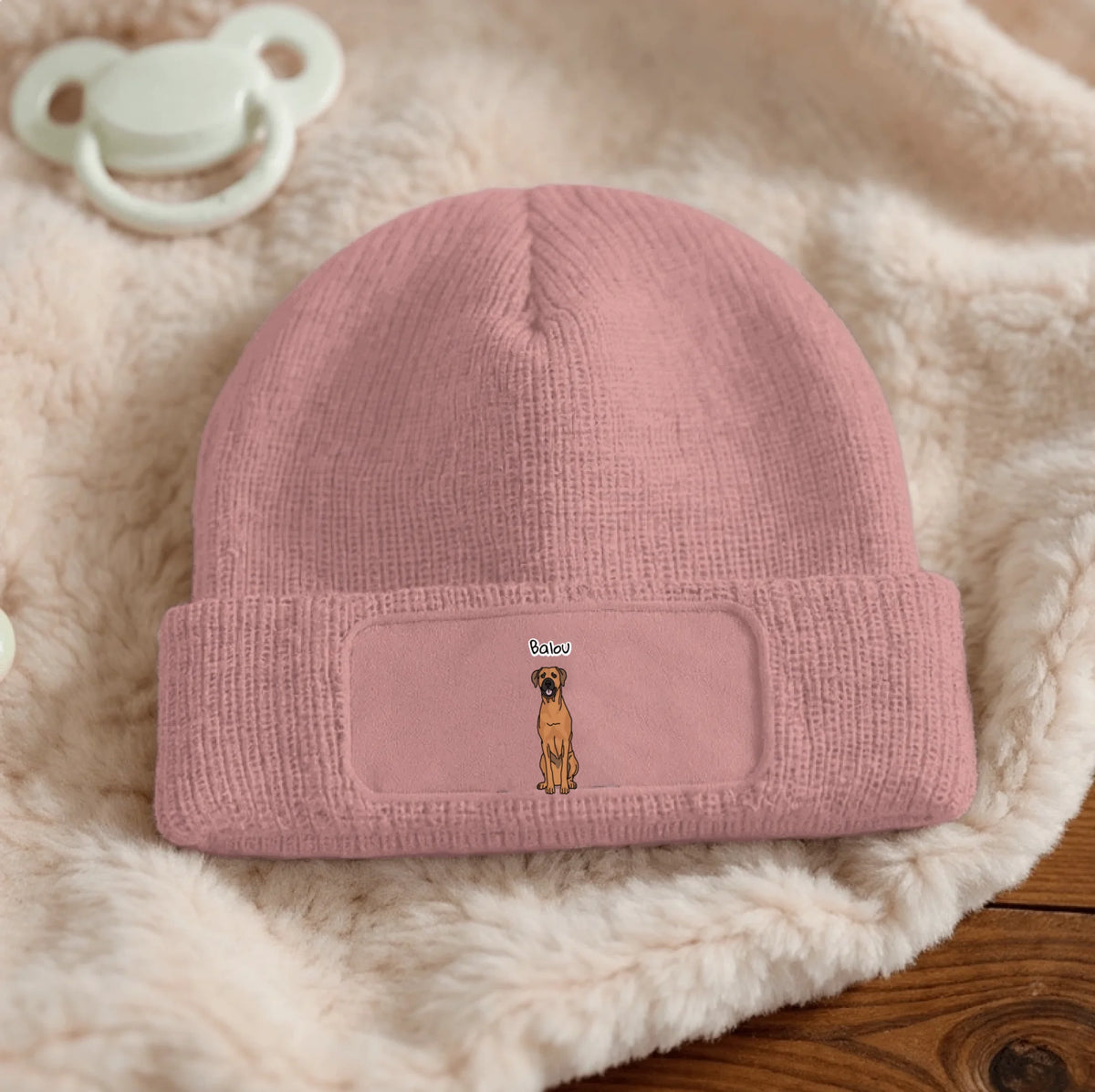 Pink knitted beanie with dog design and text field.