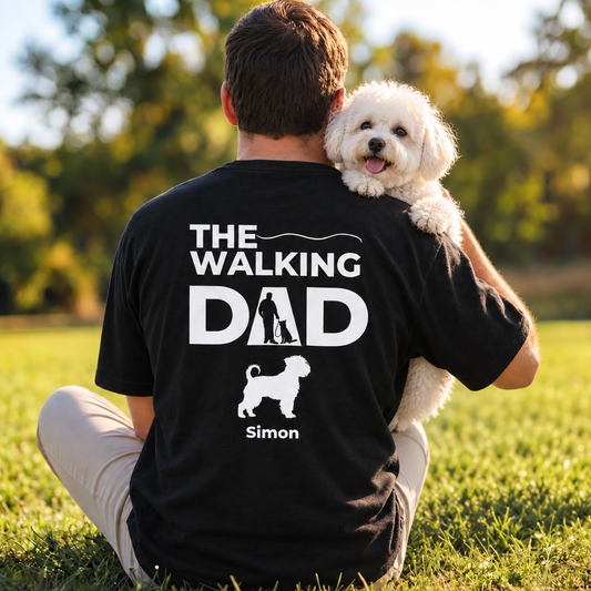 Black T-shirt printed with "The Walking Dad" and a dog motif, worn by a person outdoors.