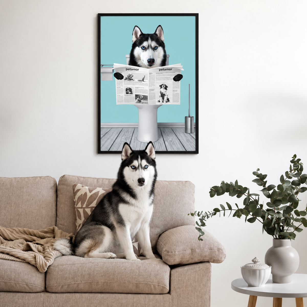 Poster of a dog reading a newspaper, in a living room above a sofa. Dog sitting on the couch.
