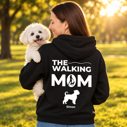 Black hoodie printed with "The Walking Mom", personalized with dog picture and name. Worn by a woman outdoors.