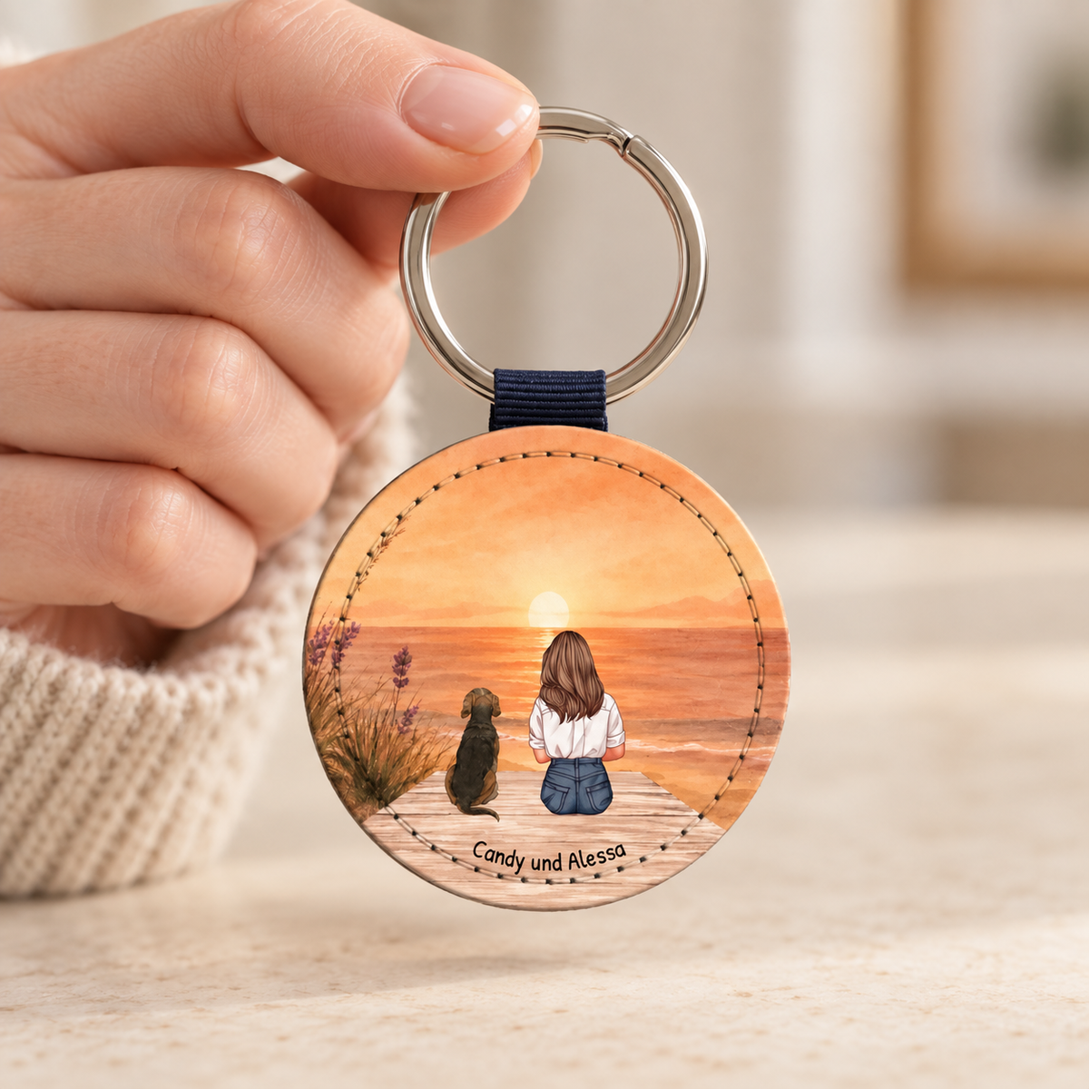 Personalized round keychain with illustration of a person and dog by the sea at sunset.