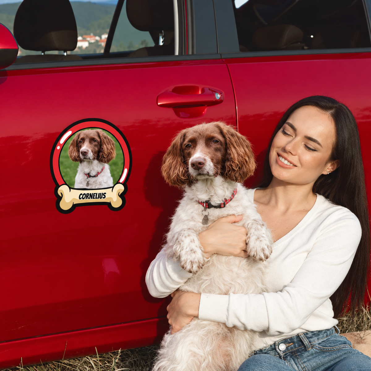 Personalized car sticker with dog picture and name on a red car, woman holding a dog in her arms.