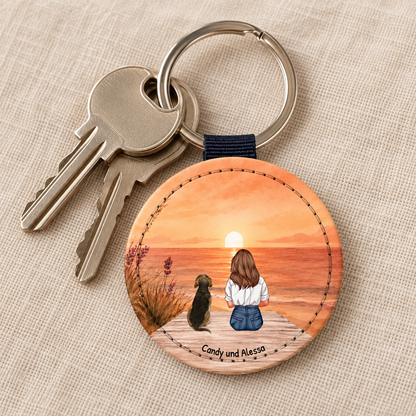 Personalized keychain showing a person and dog at sunset. Engraved wooden circle.
