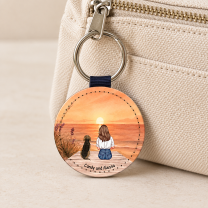Personalized keychain with illustration of a woman and a dog against a sunset.
