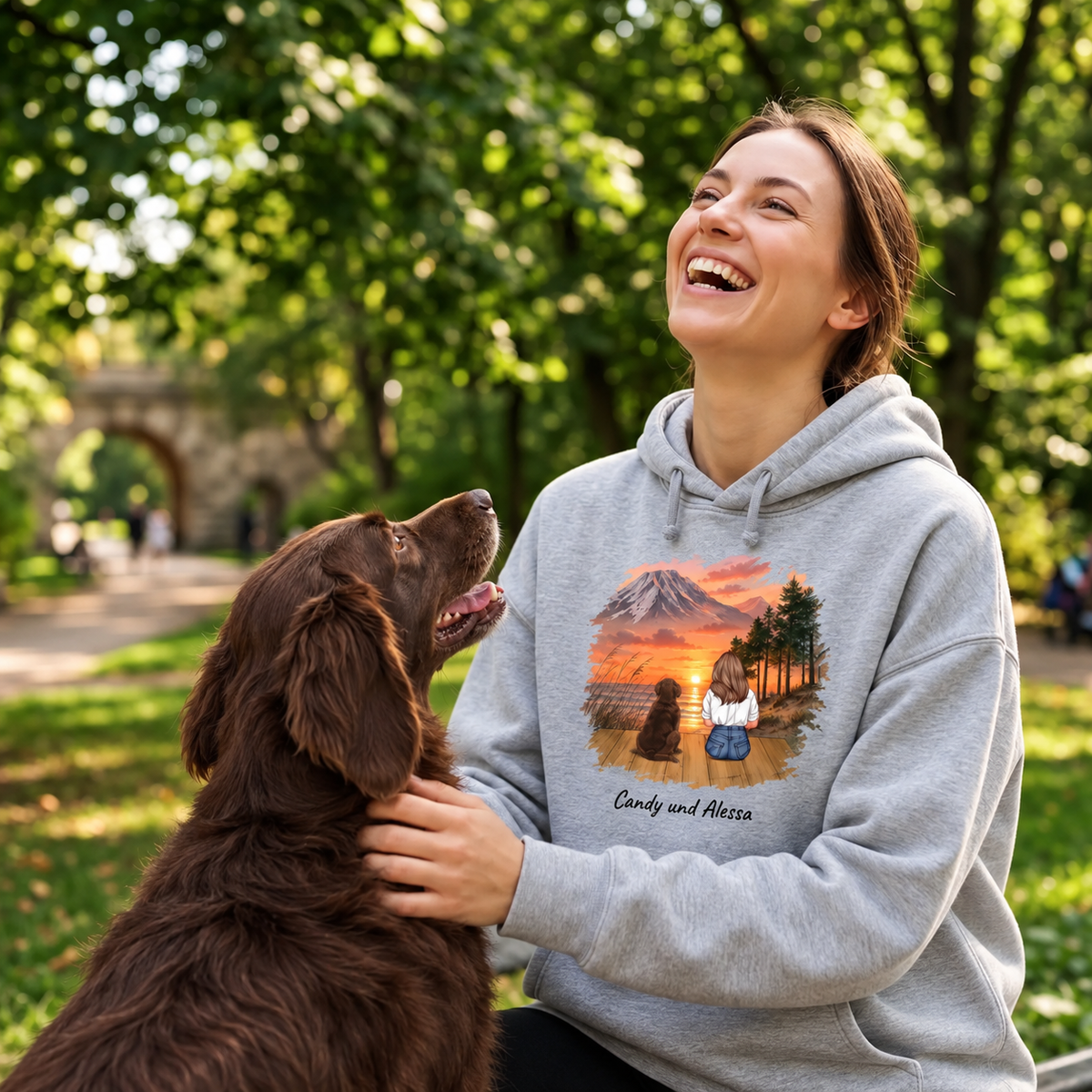 Grey hoodie with personalized print of a landscape and two animals, worn by a smiling woman.