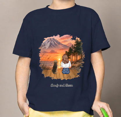 Blue kids' T-shirt with a graphic of a sitting person and dog in a sunset landscape.