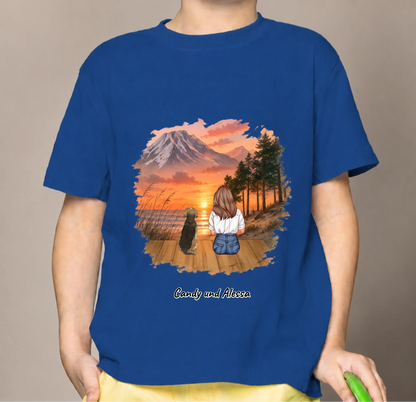 Blue kids' T-shirt with an illustration of a girl and dog watching a sunset.