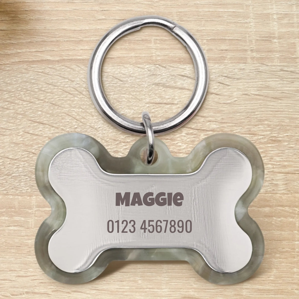 Personalized bone-shaped epoxy resin dog tag with green edge, engraved with name and phone number.