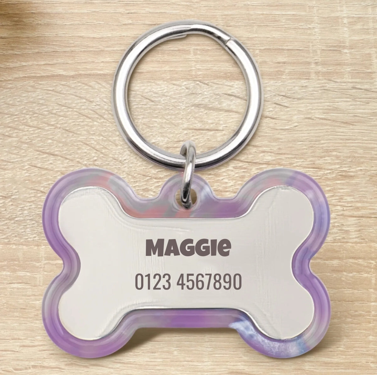 Personalized bone-shaped epoxy resin dog tag with silver ring and transparent purple edge.