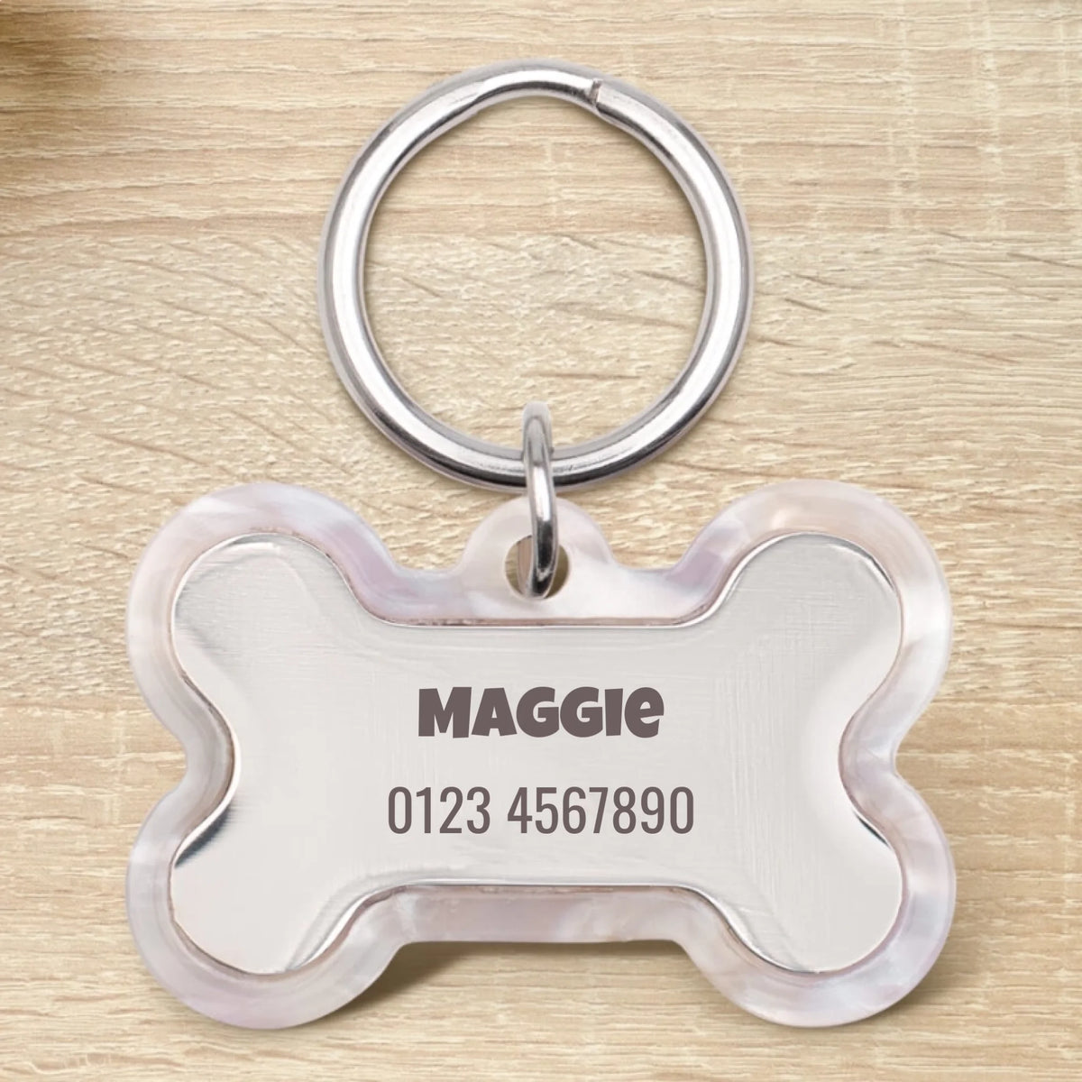 Personalized bone-shaped epoxy dog tag with the name Maggie and a phone number.
