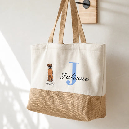 Beige tote bag with hanging handles, personalized with the initial “J” and a dog picture. Lower half made of jute.
