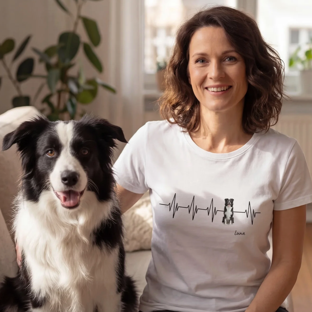 White T-shirt with heartbeat design and dog motif, personalization possible. Woman sitting on a sofa with a dog.