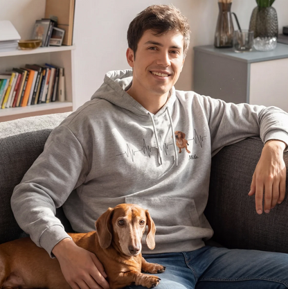 Grey hoodie with heartbeat design and dog picture, wearer sitting on a couch holding a dachshund.