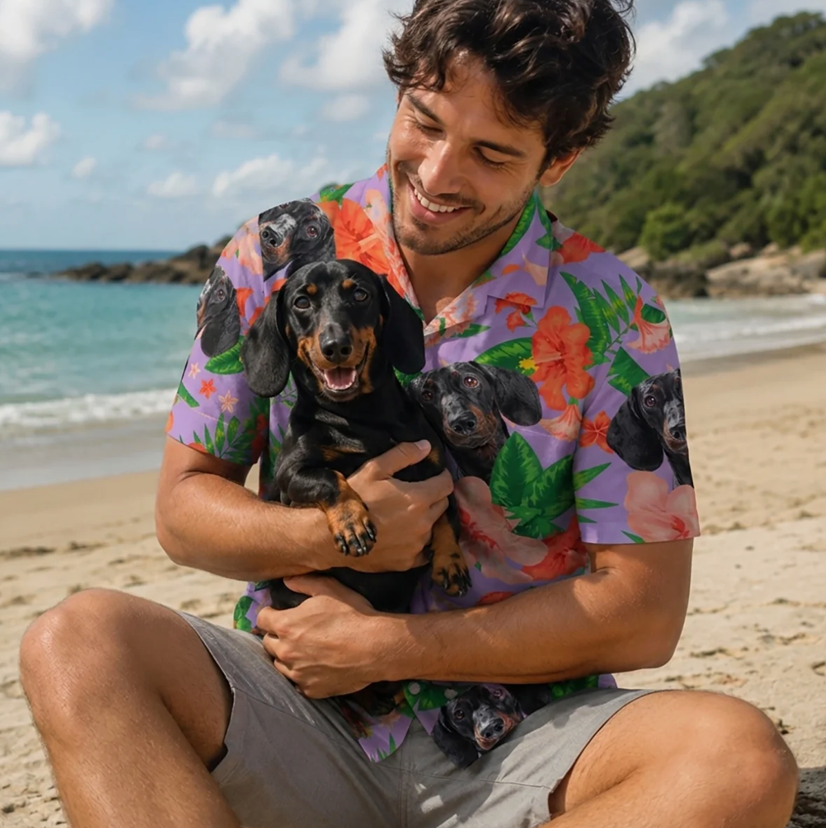 Man holding a dog and wearing a personalized Hawaiian shirt with a colourful pattern on the beach.