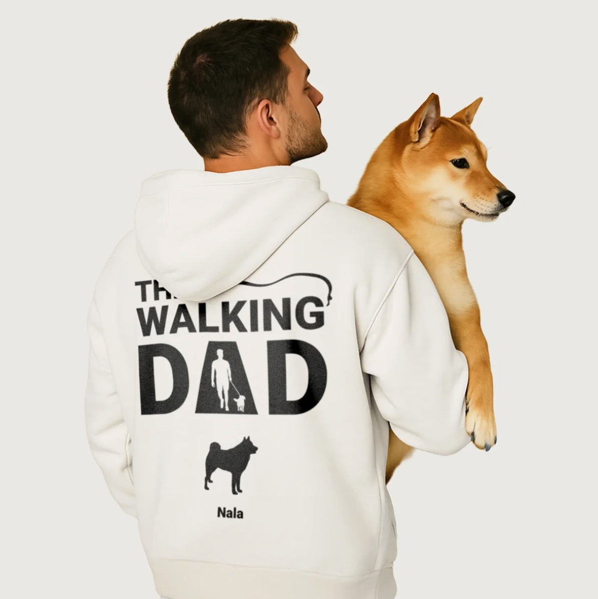 White hoodie with "THE WALKING DAD" back print and dog design, model carrying a dog.