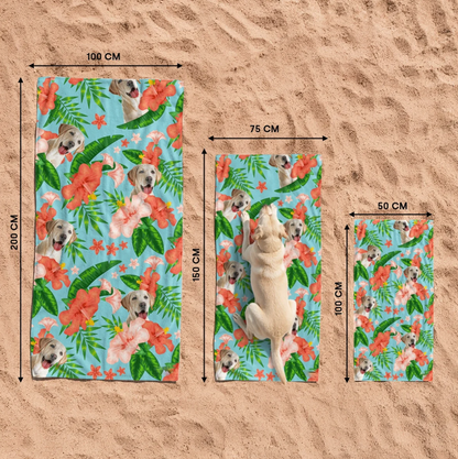 Three personalized beach towels with dog motif and colourful flowers on sandy ground.
