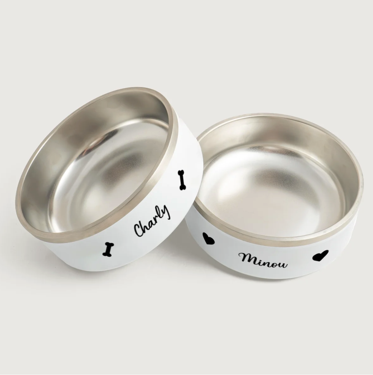 Personalized stainless steel pet bowls with white exterior, printed with the names Charly and Minou.