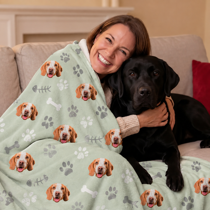 Personalized mint green pet blanket with dog motifs, woman hugging a black dog on a sofa.