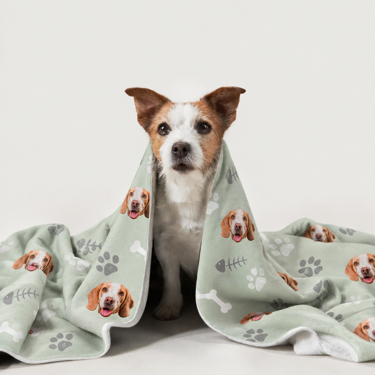 Dog wrapped in a personalized blanket with dog motifs on a green background.